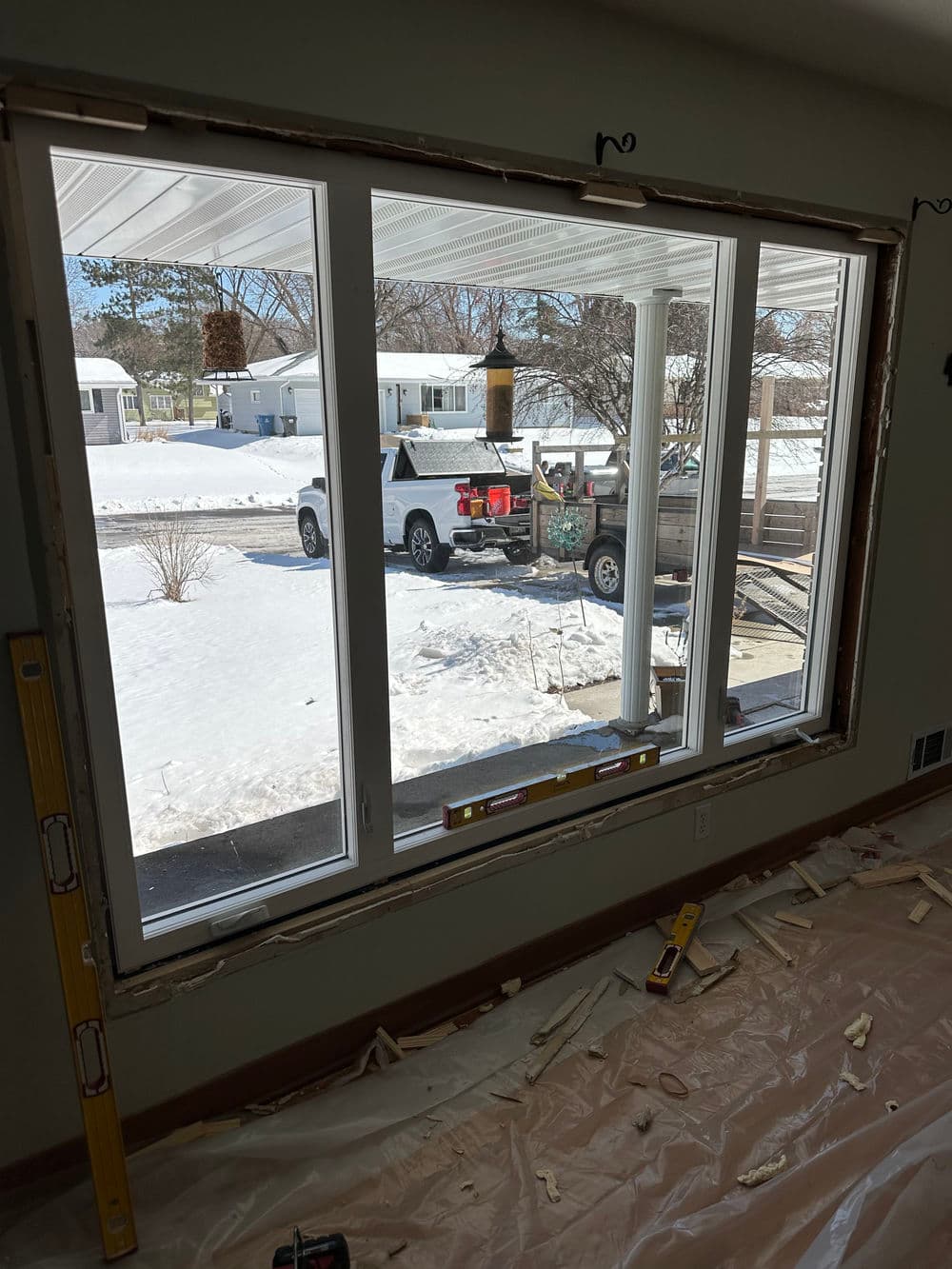 Newly installed large window overlooking snowy landscape and parked truck outside.