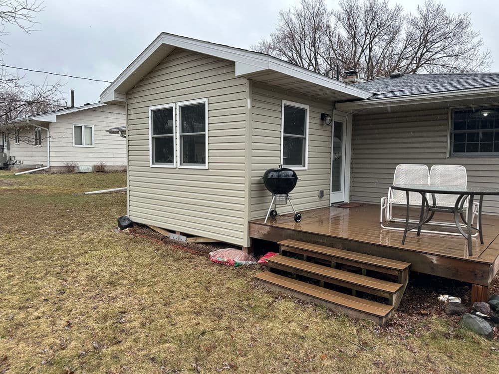 Cozy backyard patio with a grill and seating area, featuring a beige house exterior.