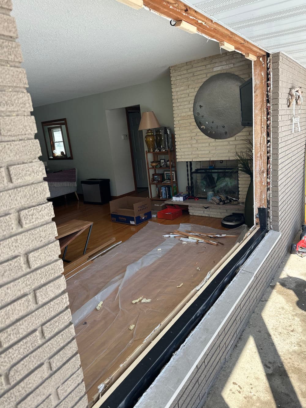 Interior renovation showing a partially removed wall with exposed structure and living room view.