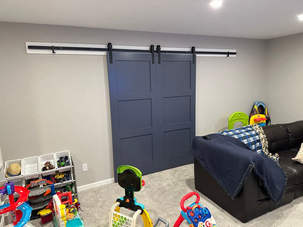 Stylish sliding barn door in modern playroom with colorful toys and cozy couch.