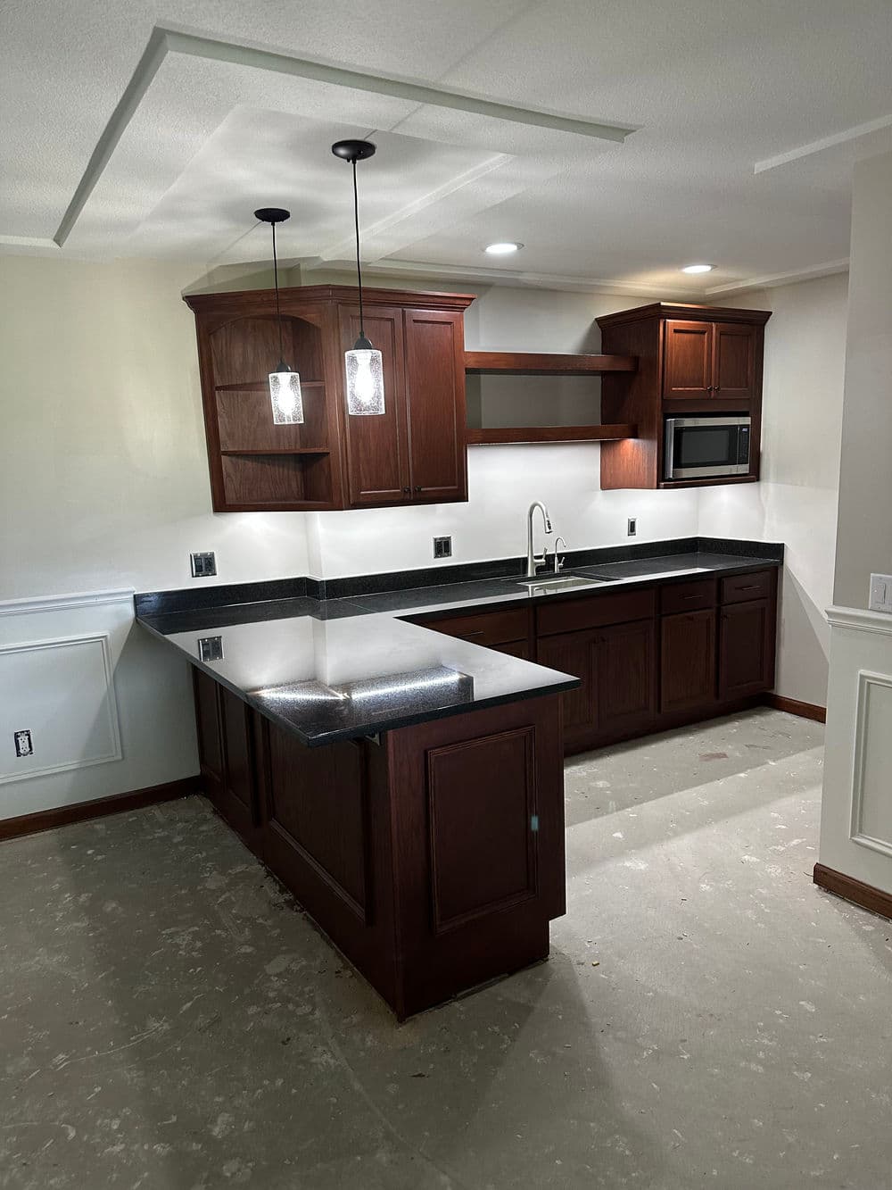 Modern kitchen renovation with dark wood cabinets, stainless steel appliances, and pendant lighting.