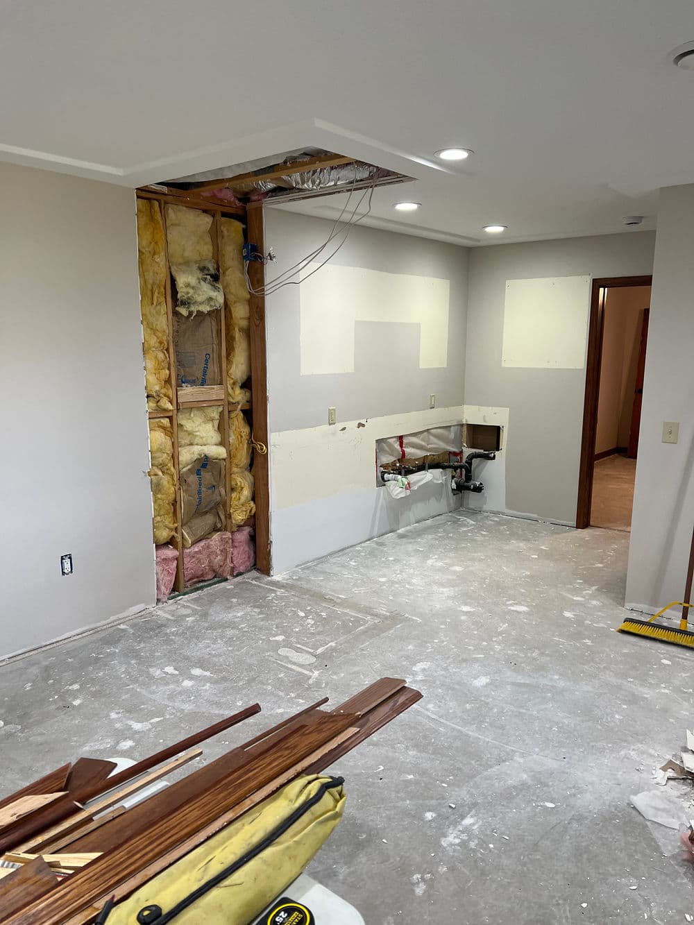 Interior renovation in progress with exposed walls, insulation, and flooring in a home.
