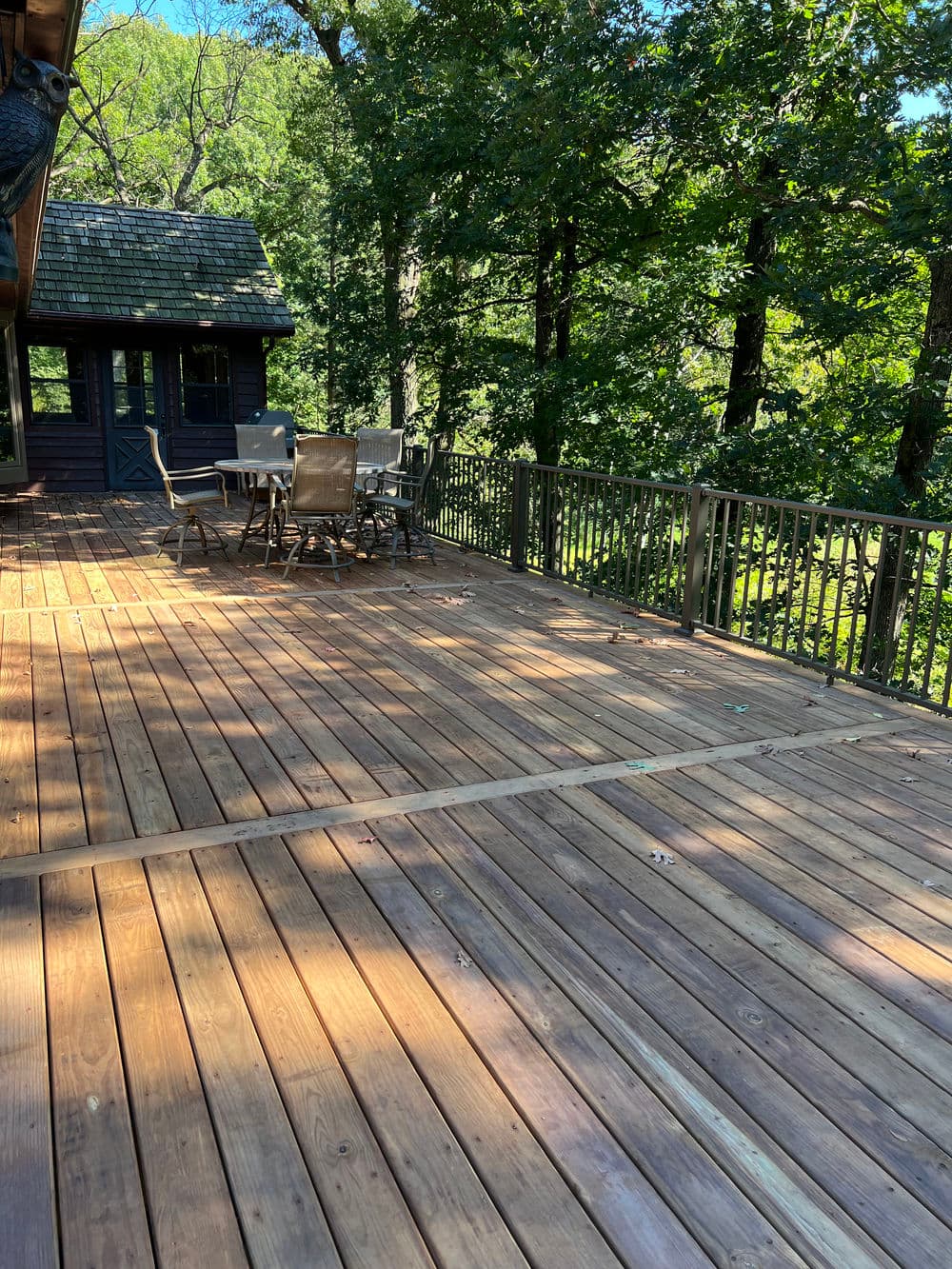 Spacious wooden deck with seating overlooking a lush forested area.