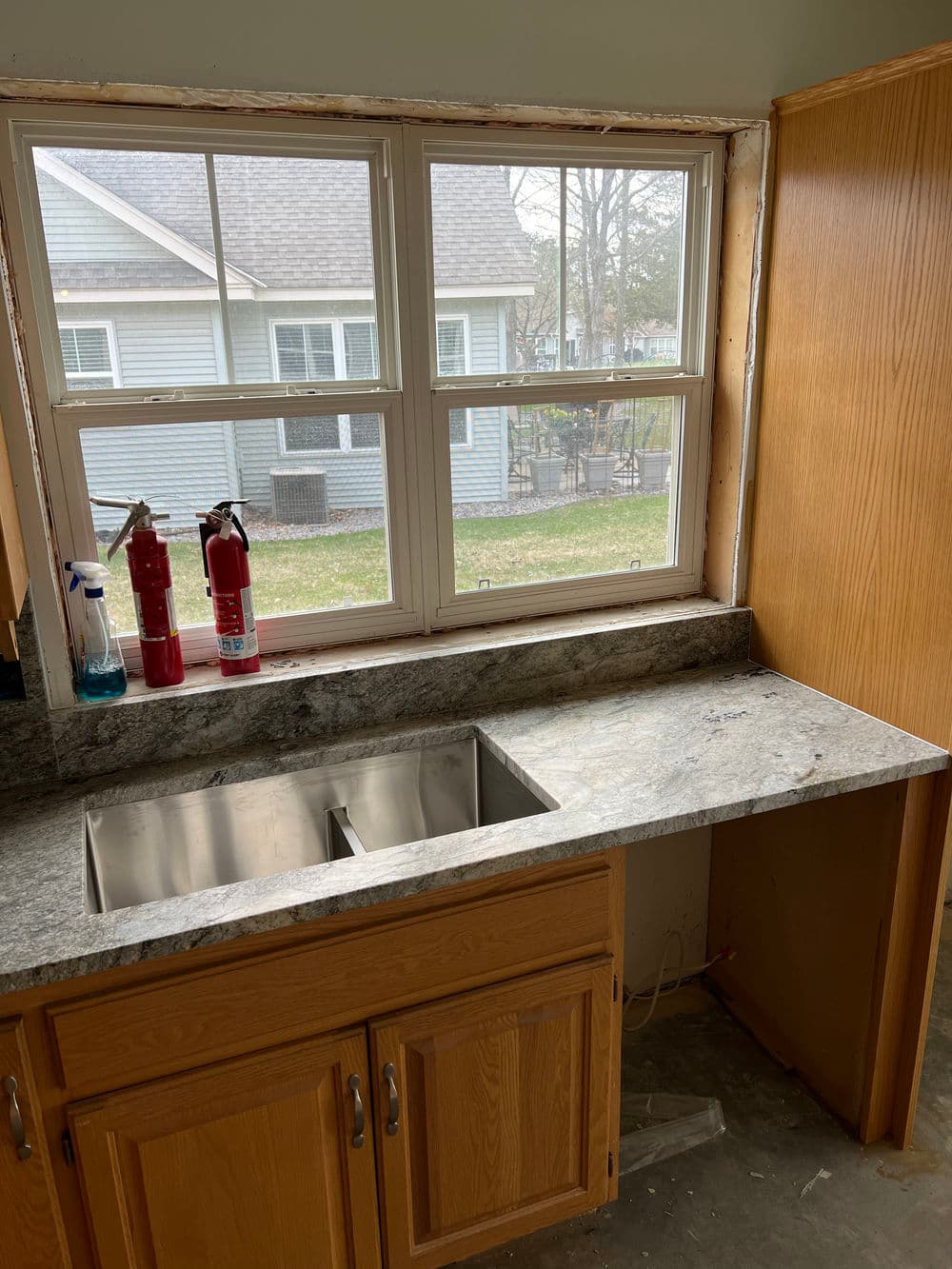 Modern kitchen featuring a double sink, granite countertop, and a window with outdoor view.