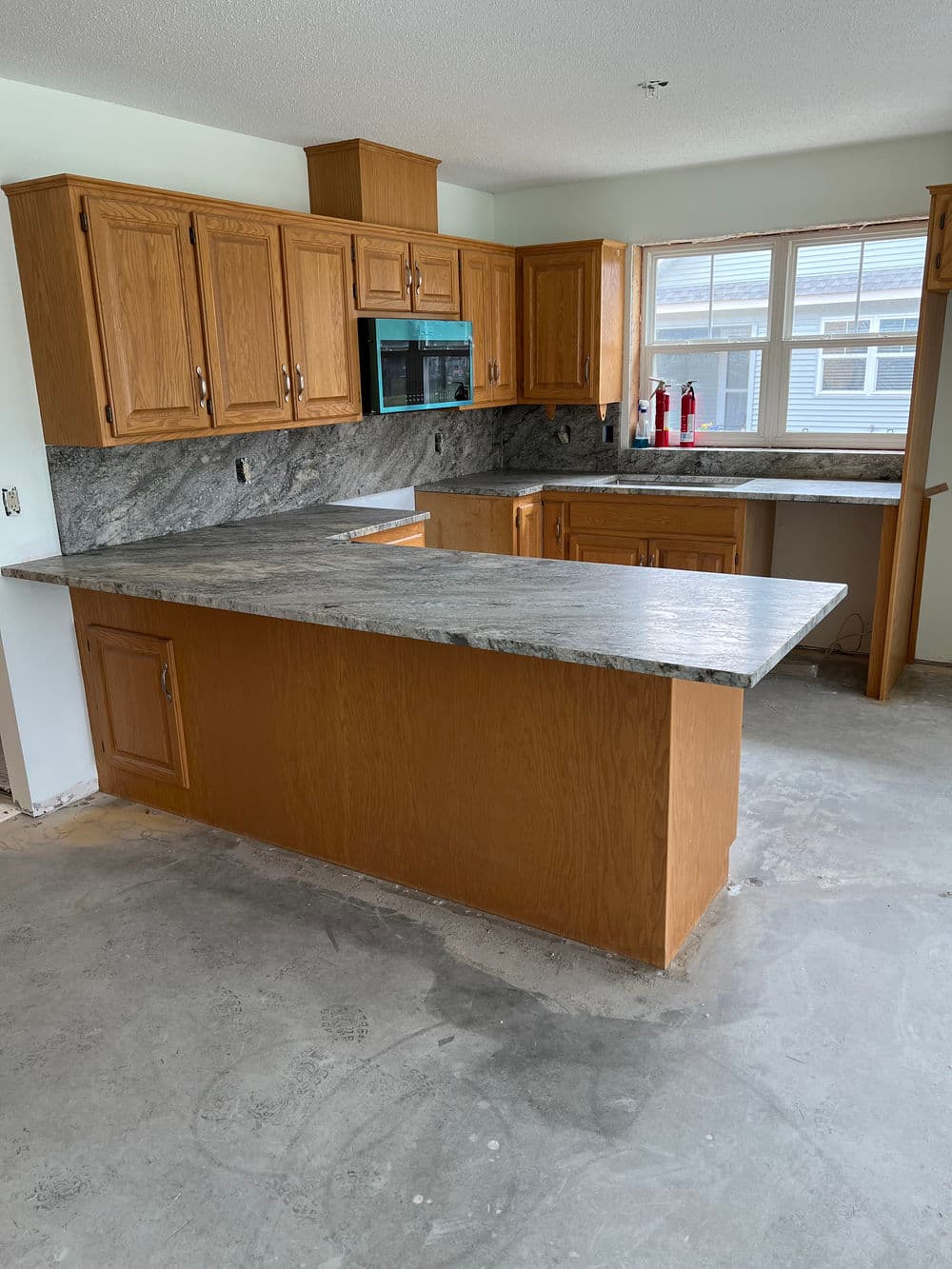Modern kitchen with wooden cabinets, granite countertops, and large windows for natural light.