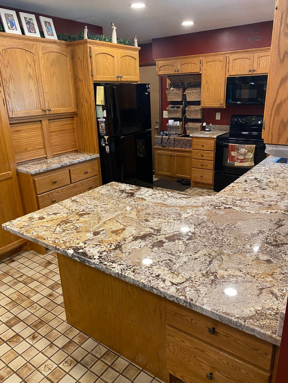 Modern kitchen with wooden cabinets, granite countertops, and tiled flooring.