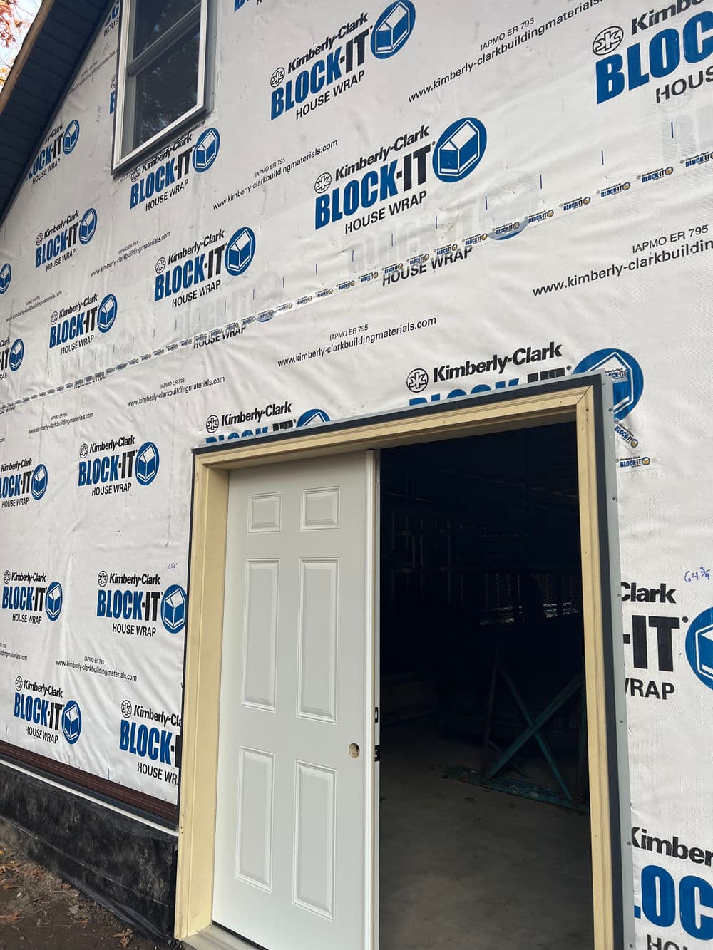 House under construction with BLOCK-IT house wrap by Kimberly-Clark and open door.
