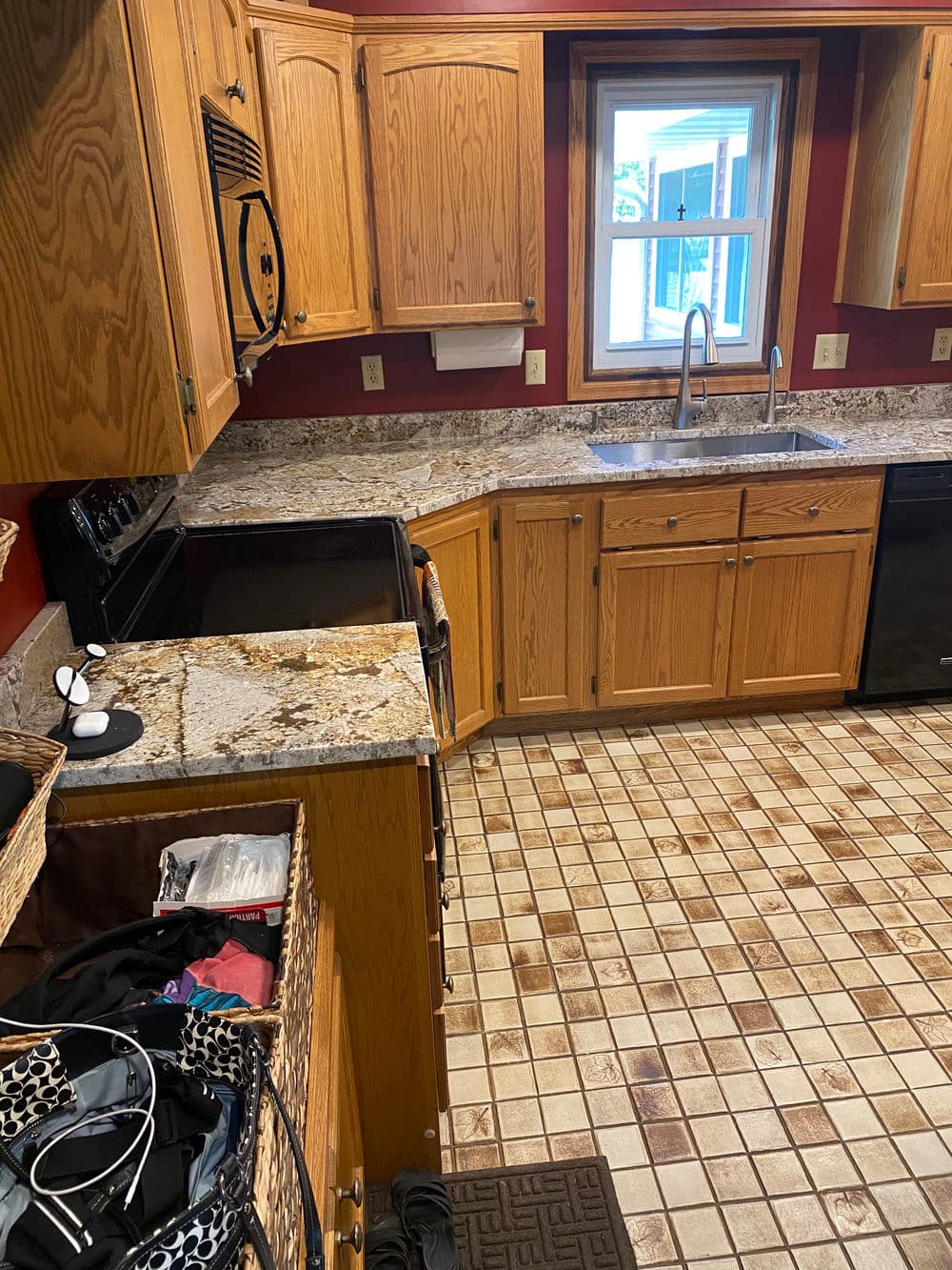 Modern kitchen with wooden cabinets, granite countertops, and a tiled floor. Organized and bright.