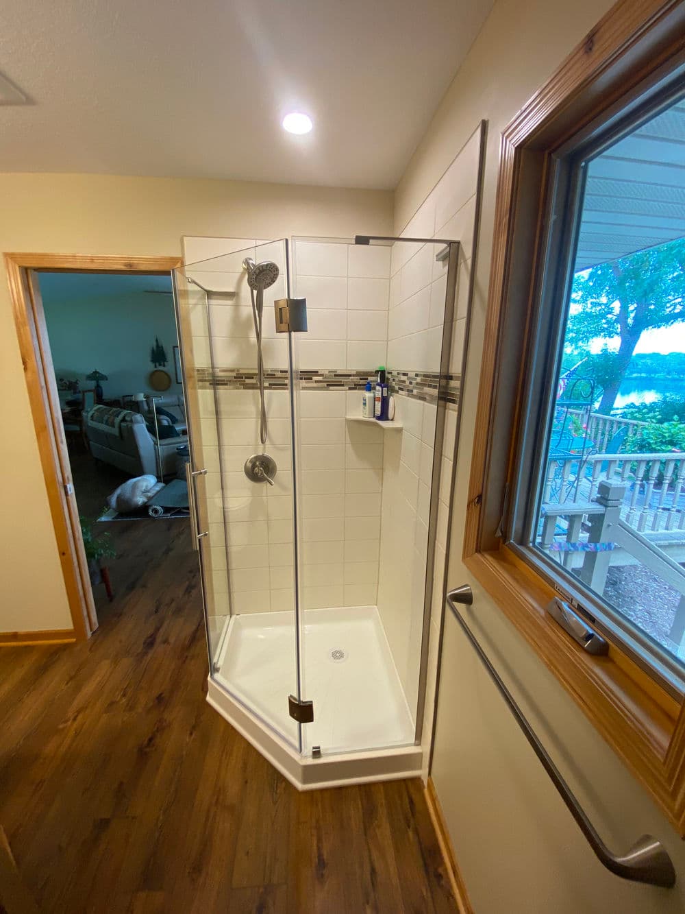 Modern corner shower with glass doors, tile accents, and a view of a scenic outdoor space.