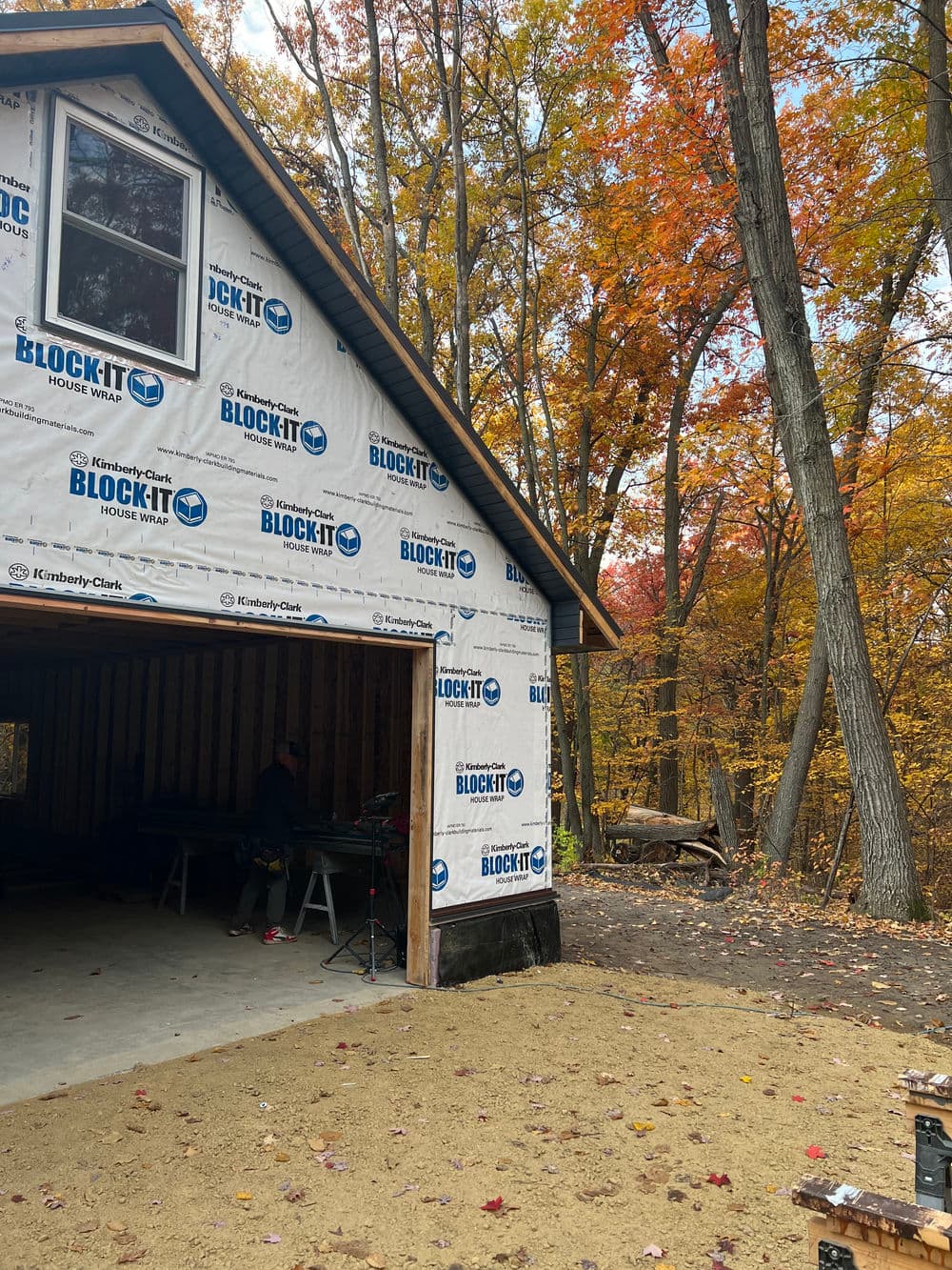 Newly constructed garage with Block-It house wrap, surrounded by autumn foliage.