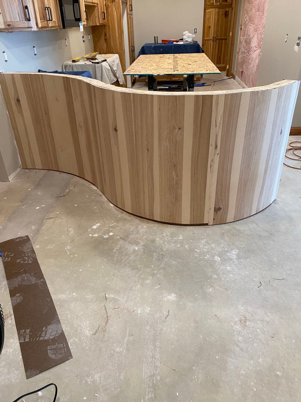 Curved wooden countertop in a modern kitchen renovation with light wood grain details.