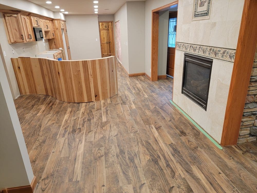 Modern interior of a home featuring hardwood flooring, a curved wooden bar, and a fireplace.