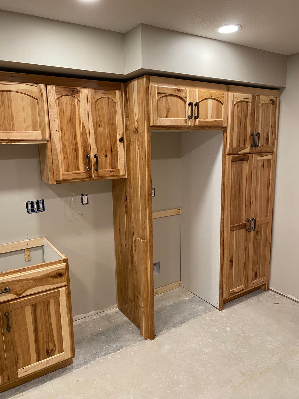 Modern kitchen renovation with custom wooden cabinets and unfinished walls.