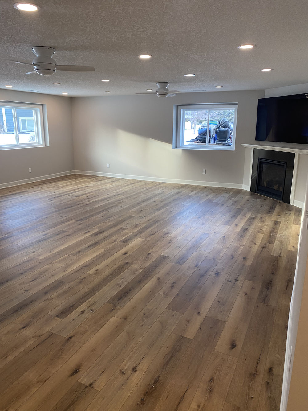 Spacious modern living room with hardwood floors, large windows, and a fireplace.