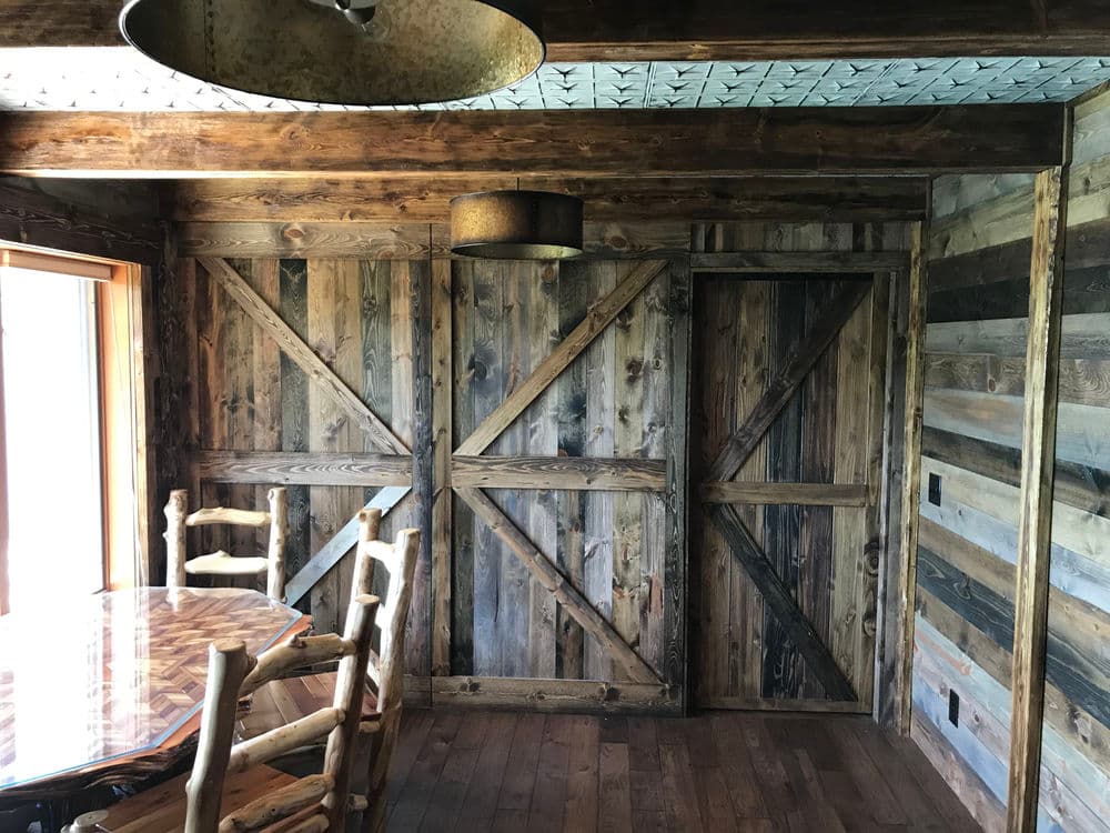 Rustic wooden interior with cross-pattern doors, a dining table, and natural light.