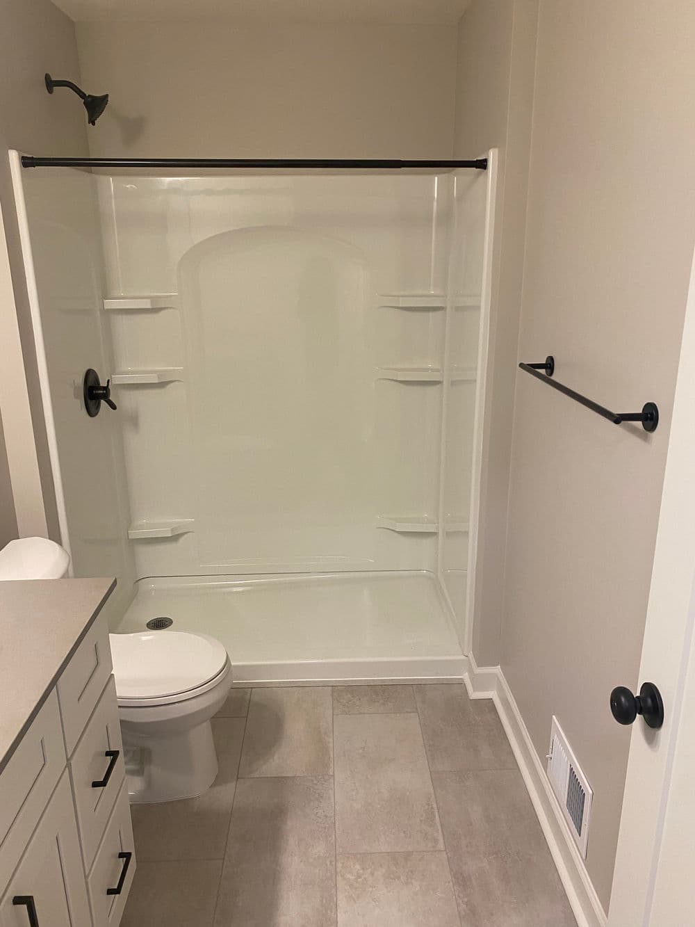 Modern bathroom featuring a shower stall, toilet, and neutral tile flooring.